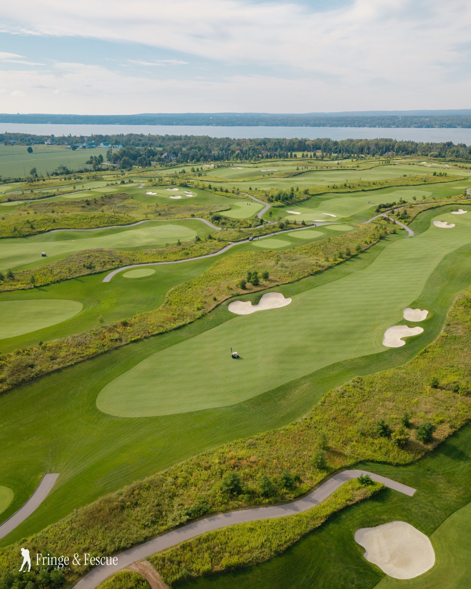 Drone aerial of The Nest Golf Club at Friday Harbour: fescue-lined fairways, bunkers and Lake Simcoe on the horizon, by Fringe & Fescue